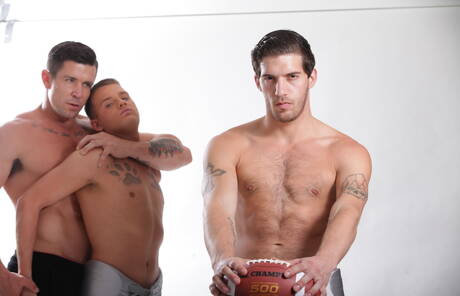 Sporty gays Aiden, Alexander and Brandon posing in football uniform